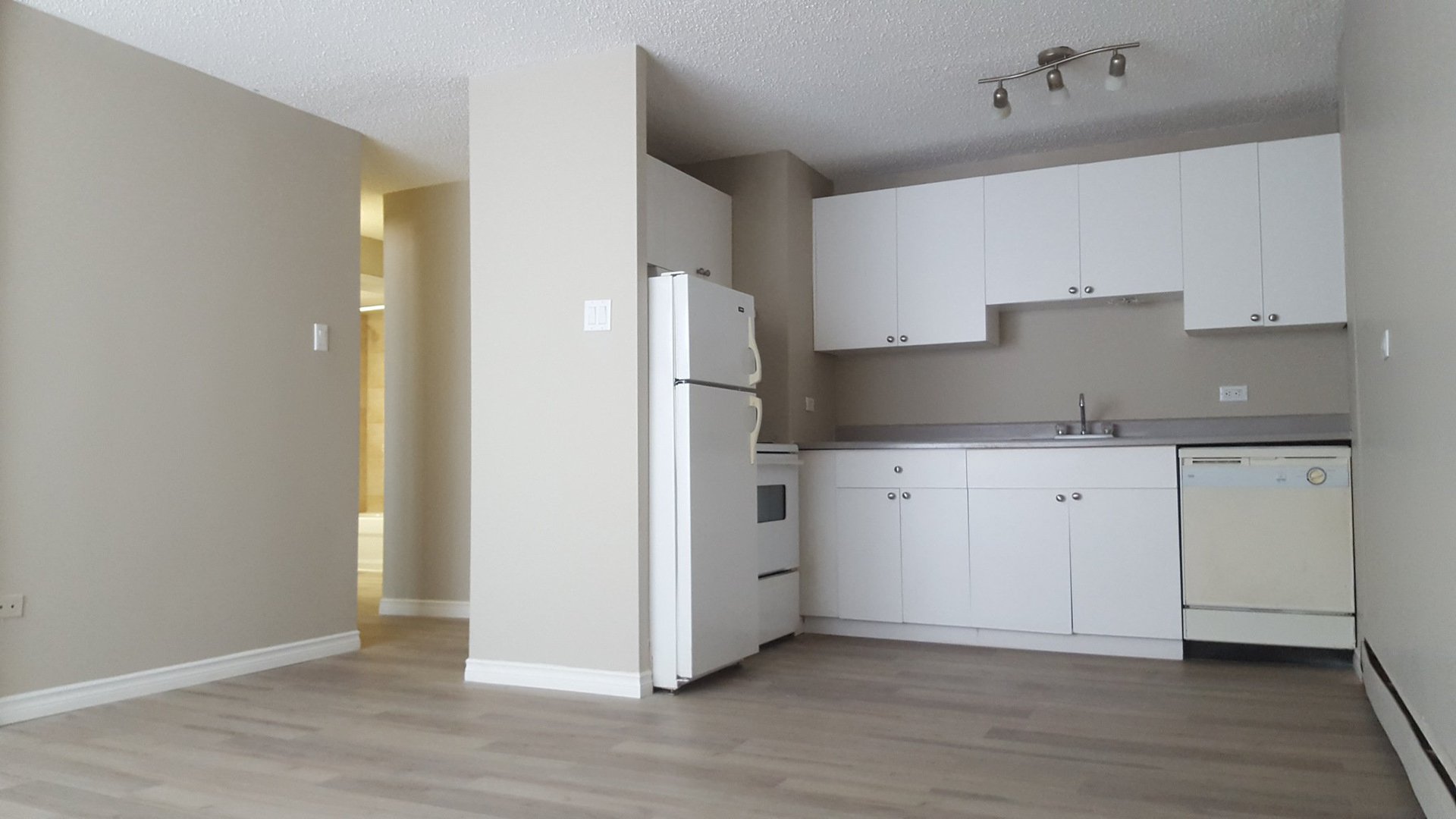 Apartment for rent at 211 14 Avenue SW, Calgary, AB. This is the kitchen. It has hardwood floor, dishwasher, radiator and refrigerator.