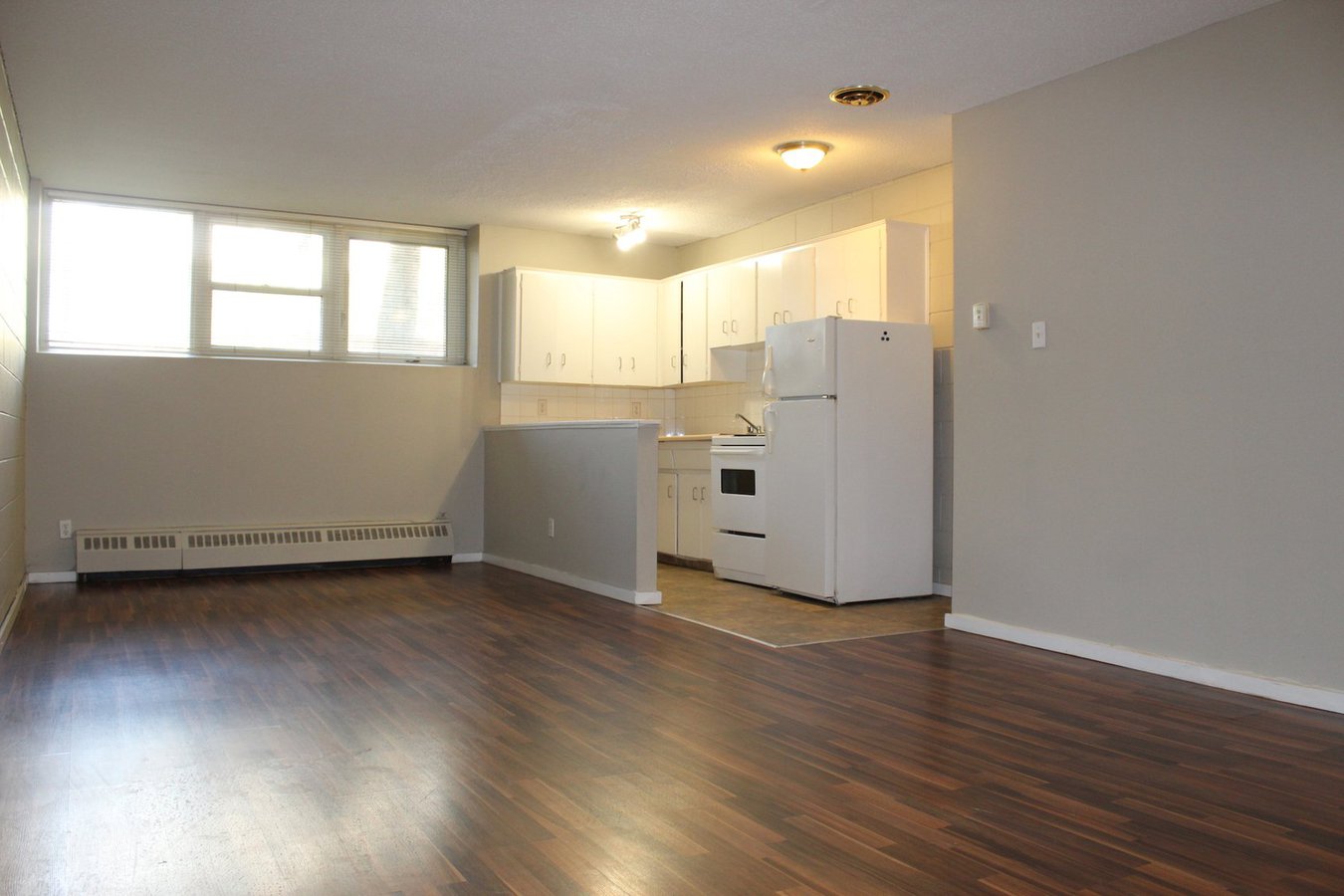 Apartment for rent at 1639 26 Avenue SW, Calgary, AB. This is the kitchen. It has hardwood floor, tile floor, natural light, oven, radiator and refrigerator.